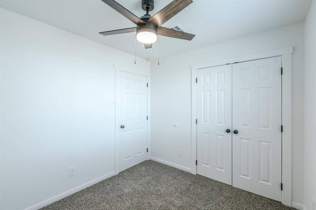 4133 Sherry Lane, Beverly Hills, TX 76711 Ceiling fan with light fixture, paneled bi-fold doors, paneled interior door, and textured carpeting