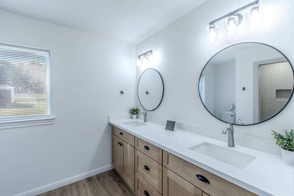 4133 Sherry Lane, Beverly Hills, TX 76711 Dual vanity with light wood-finish cabinetry, integrated rectangular sinks, and brushed nickel faucets
