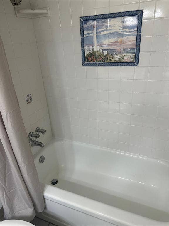 6050 Birchbrook Drive, #242, Dallas, TX 75206 White tiled shower surround with a built-in corner shelf and polished chrome fixtures