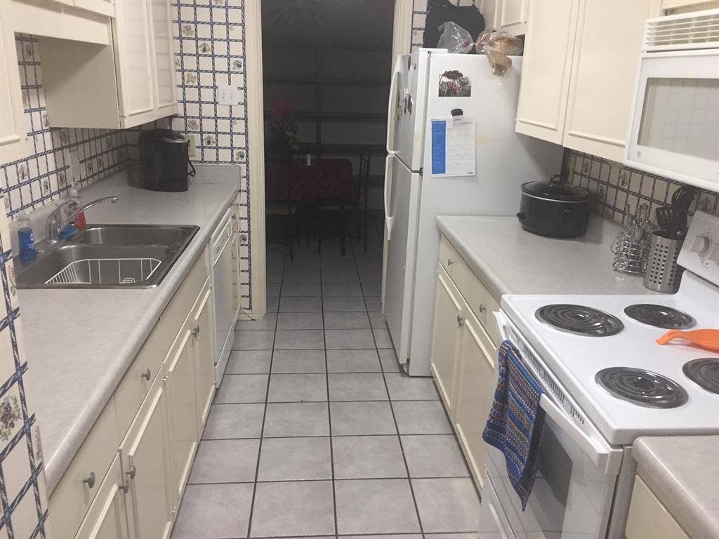 6050 Birchbrook Drive, #242, Dallas, TX 75206 Galley kitchen featuring white cabinetry, light countertops, a stainless steel double basin sink, and tile flooring
