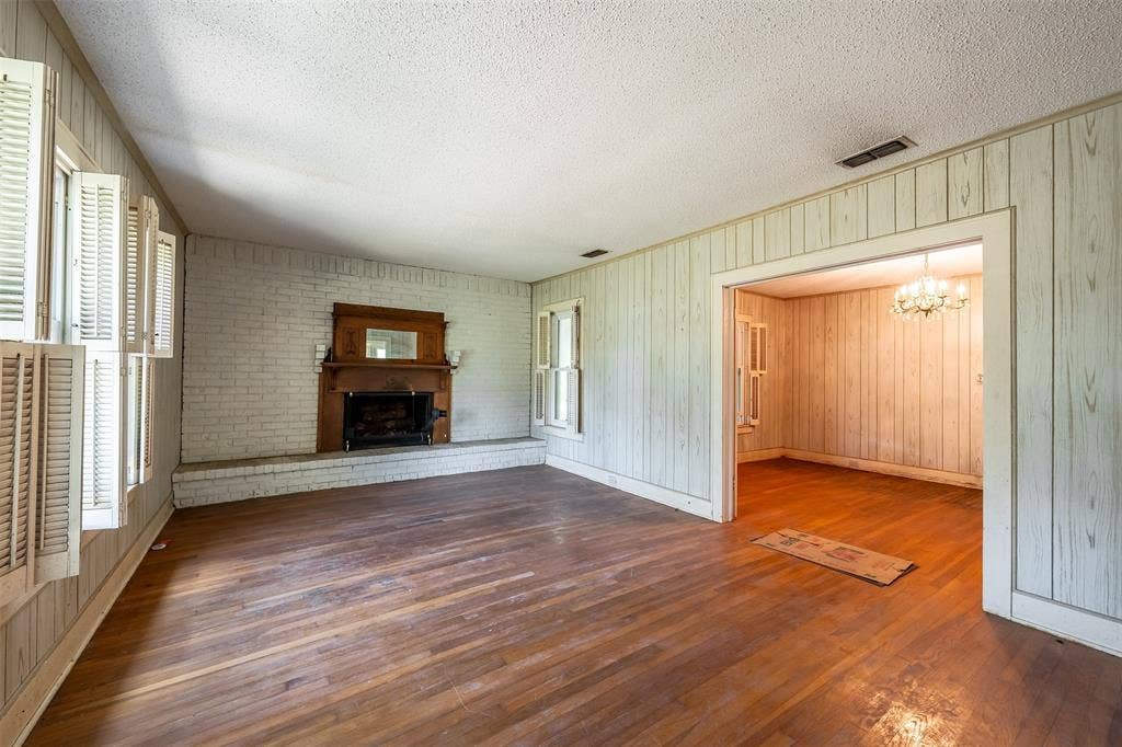 5250 Fm 2494, Athens, TX 75751 Hardwood flooring, brick fireplace with wood mantel, paneling, open doorway, and a chandelier in the adjacent space
