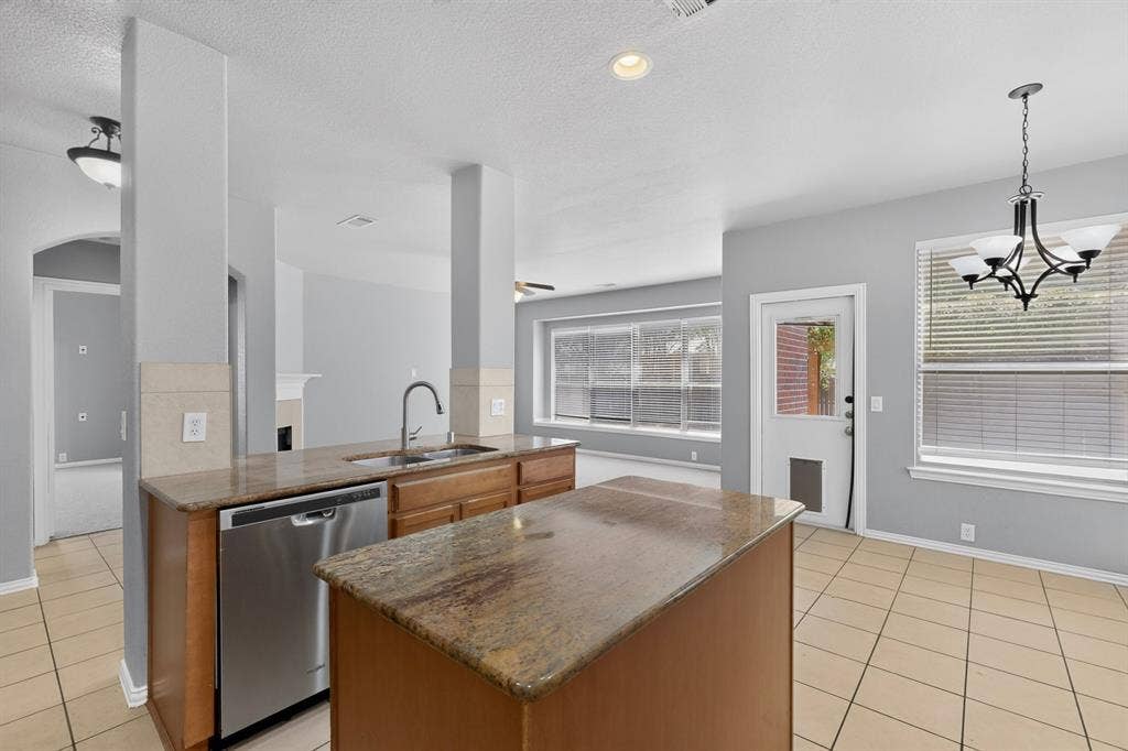Kitchen island featuring an undermount sink and a stainless steel dishwasher