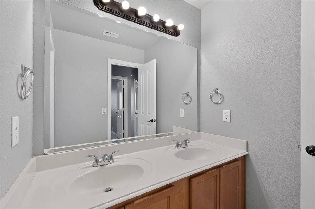 Dual vanity with integrated sinks, wood-finish cabinetry, and a full-width mirror