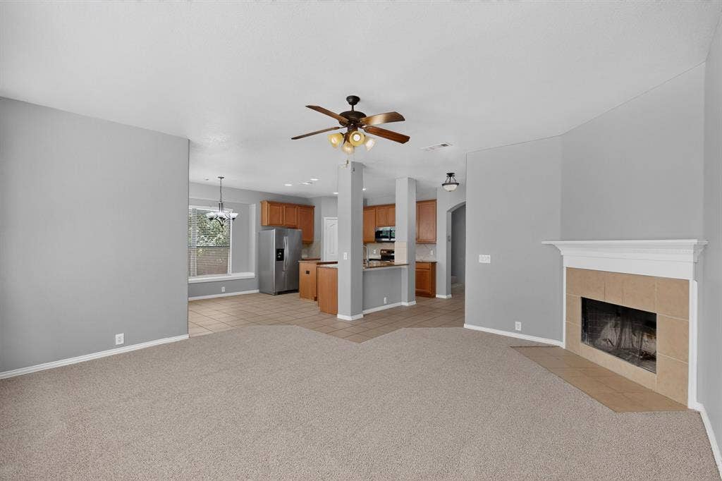 Built-in fireplace with tile surround and mantel, overhead ceiling fan, and carpeted flooring
