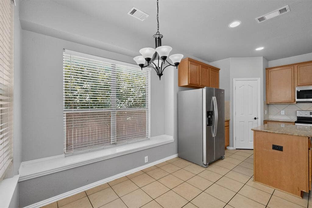 Kitchen with wood cabinetry, tile flooring, a built-in window seat, and a chandelier
