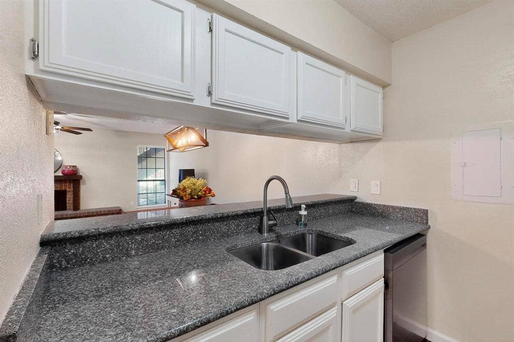 Kitchen featuring white cabinetry, gray speckled countertops, a double basin stainless steel sink with a high arc faucet, and a stainless steel dishwasher