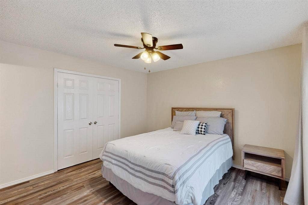 Wood-finish flooring, ceiling fan with integrated lighting, and a double bi-fold closet