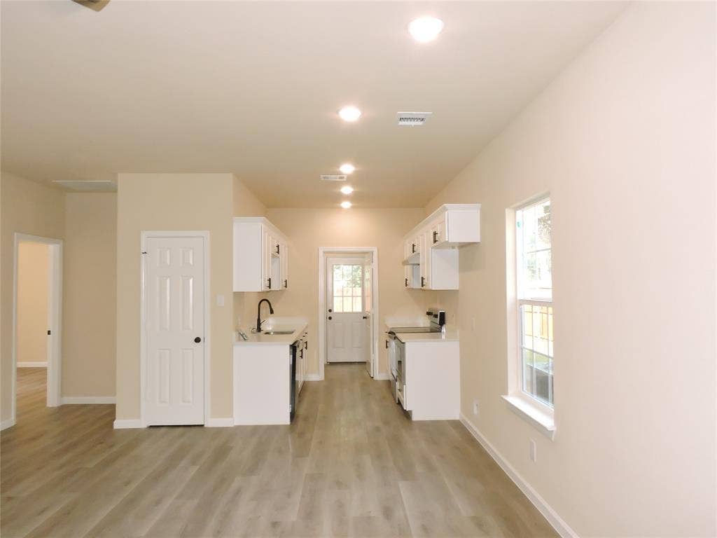 106 Navajo Drive, Mabank, TX 75156 Open-concept kitchen with white cabinetry, wood-finish flooring, recessed lighting, and a white sink with a matte black faucet