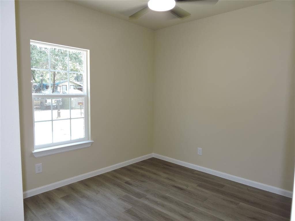 106 Navajo Drive, Mabank, TX 75156 Neutral tone walls, wood-finish flooring, white window trim, and a ceiling fan with integrated lighting