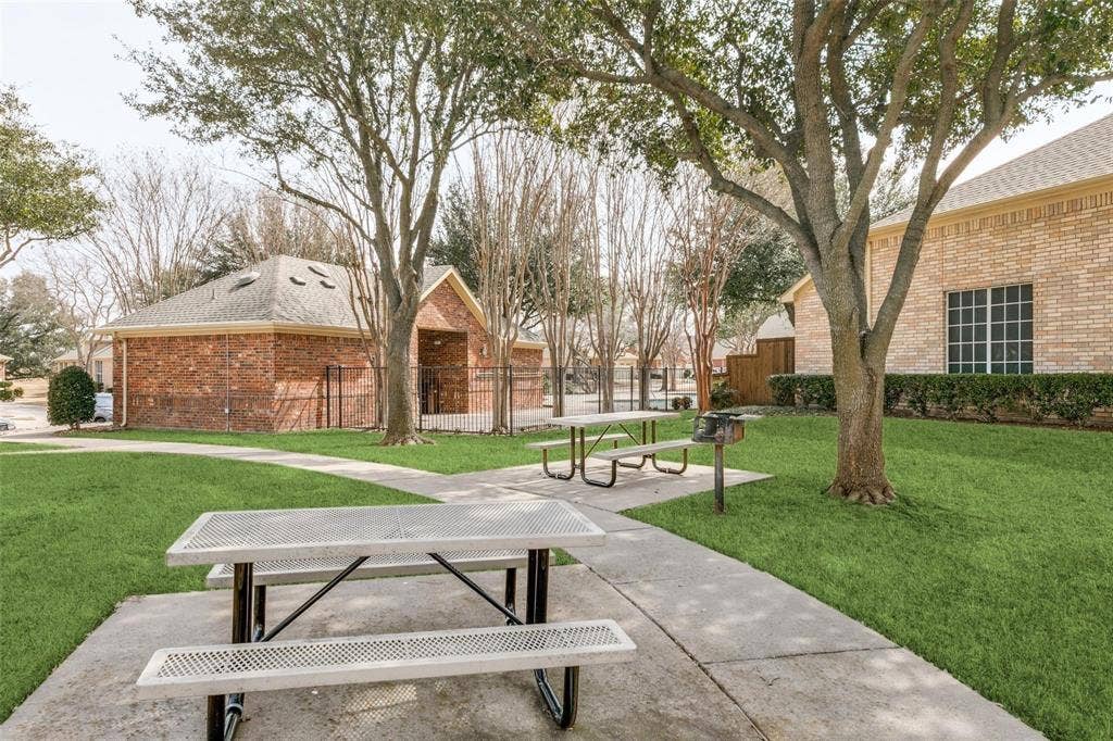 2829 Mott Street, Plano, TX 75025 Manicured lawn area with concrete pathways, mature trees, and a brick-clad structure