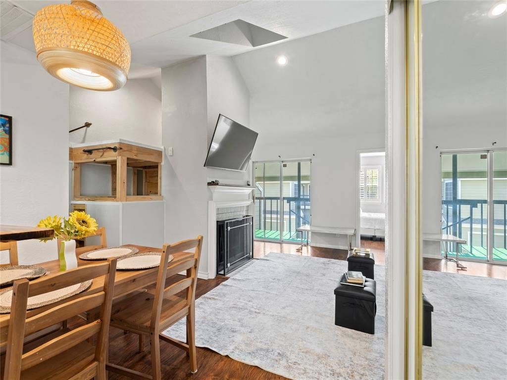 6220 Bentwood Trail, #205, Dallas, TX 75252 Vaulted ceiling, wood-finish flooring, built-in fireplace, sliding glass doors, and a decorative light fixture