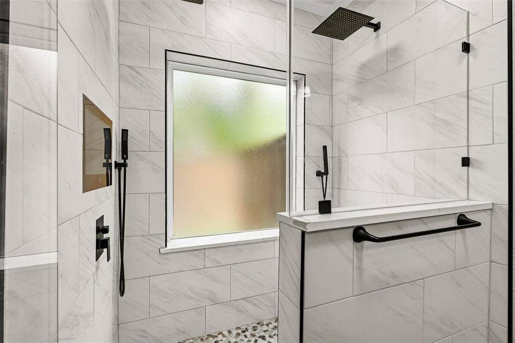 2705 Ithaca Court, Plano, TX 75025 Tiled shower enclosure featuring a fixed glass panel, pebble floor, and matte black fixtures