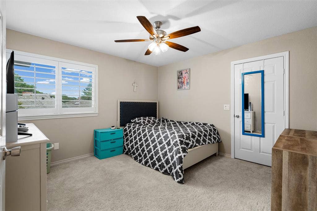 2705 Ithaca Court, Plano, TX 75025 Carpeted room featuring a ceiling fan with light, a window with plantation shutters, and a white door