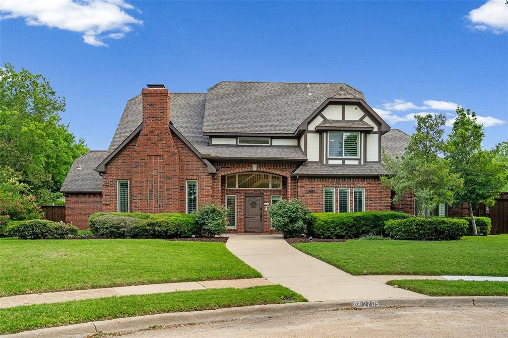 2705 Ithaca Court, Plano, TX 75025 Brick and Tudor-style exterior with gabled roof lines, featuring a prominent brick chimney, arched entry, and mature landscaping