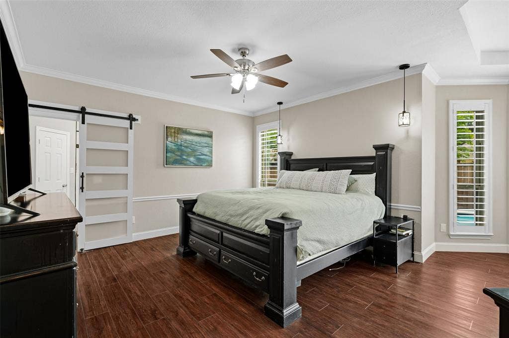 2705 Ithaca Court, Plano, TX 75025 Wood-finish flooring, crown molding, ceiling fan, contemporary barn door, and suspended pendant lighting fixtures