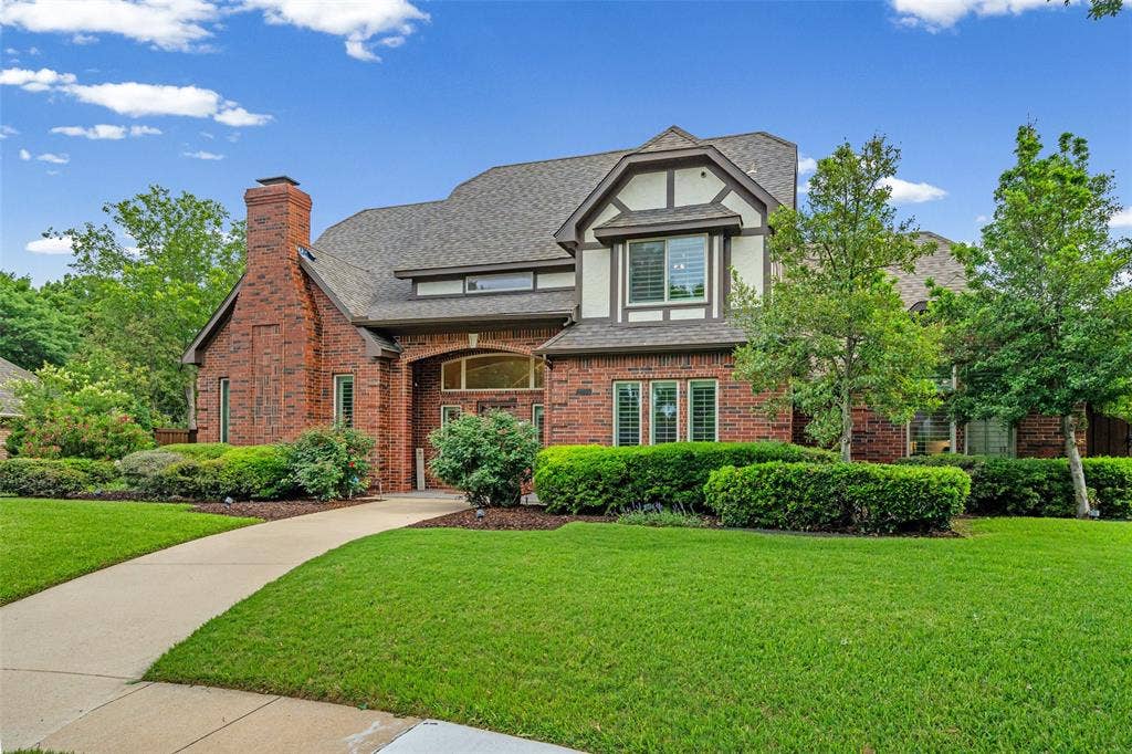 2705 Ithaca Court, Plano, TX 75025 Brick exterior with a prominent chimney, Tudor-style accents, mature landscaping, and an arched entry