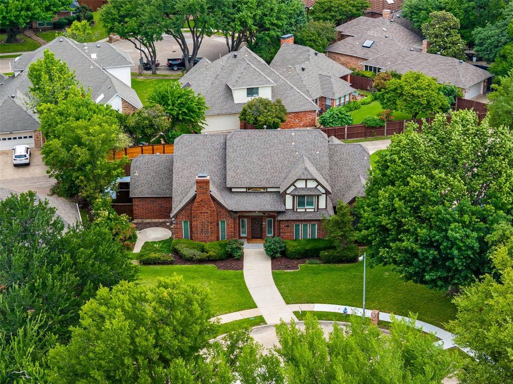 2705 Ithaca Court, Plano, TX 75025 Brick exterior with a prominent chimney, a gabled roof, and a mature tree canopy