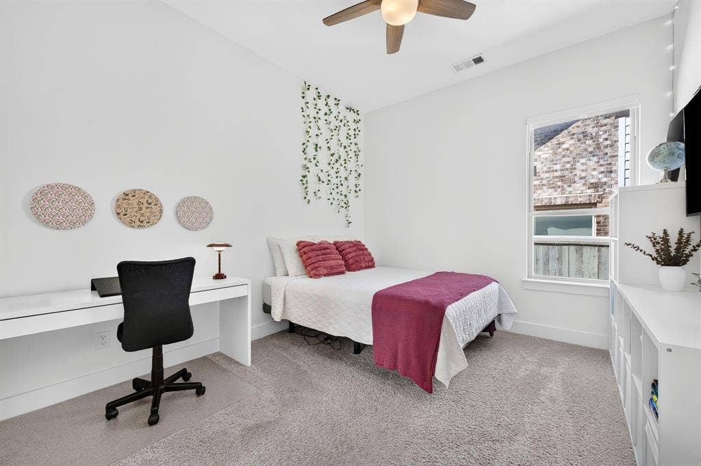 2809 Buckskin Lane, Northlake, TX 76247 Plush carpet flooring, a built-in white desk, white walls, a multi-pane window, and a ceiling fan with integrated lighting