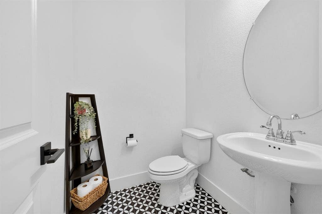 2809 Buckskin Lane, Northlake, TX 76247 Pedestal sink with chrome fixtures, round wall-mounted mirror, and patterned floor tile