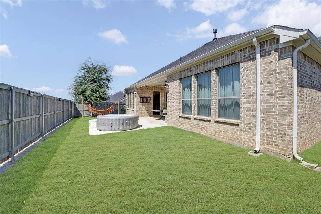 2809 Buckskin Lane, Northlake, TX 76247 Expansive lawn area with a wood privacy fence, concrete patio, and brick exterior