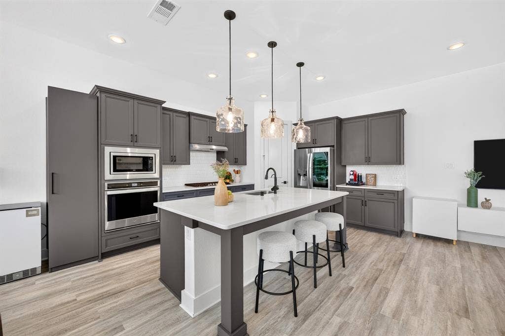 2809 Buckskin Lane, Northlake, TX 76247 Kitchen featuring wood-finish flooring, recessed lighting, a central island with a white countertop, dark gray cabinetry, and stainless steel built-in appliances