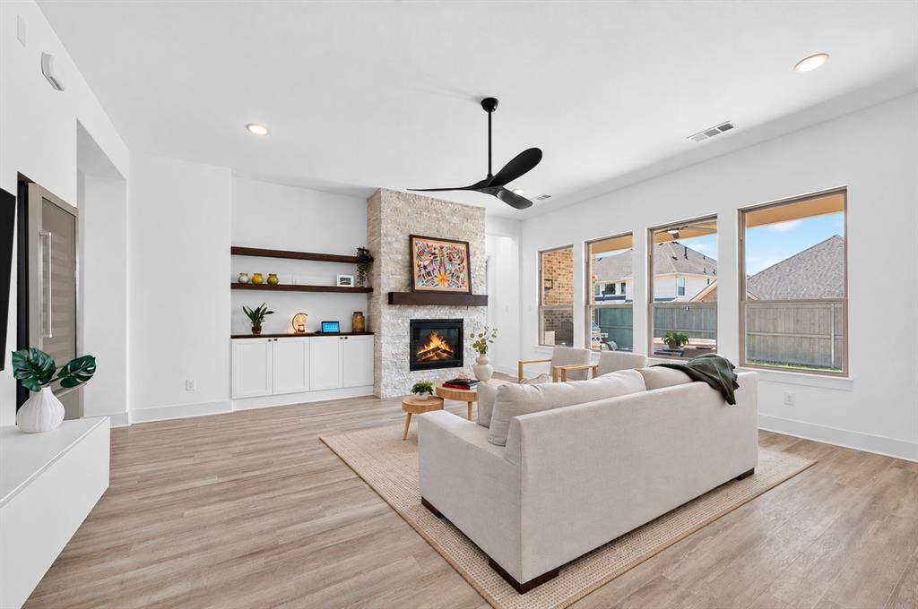 2809 Buckskin Lane, Northlake, TX 76247 Spacious living area featuring a stone-clad fireplace with a wood mantel, built-in shelving, white cabinetry, and wood-finish flooring