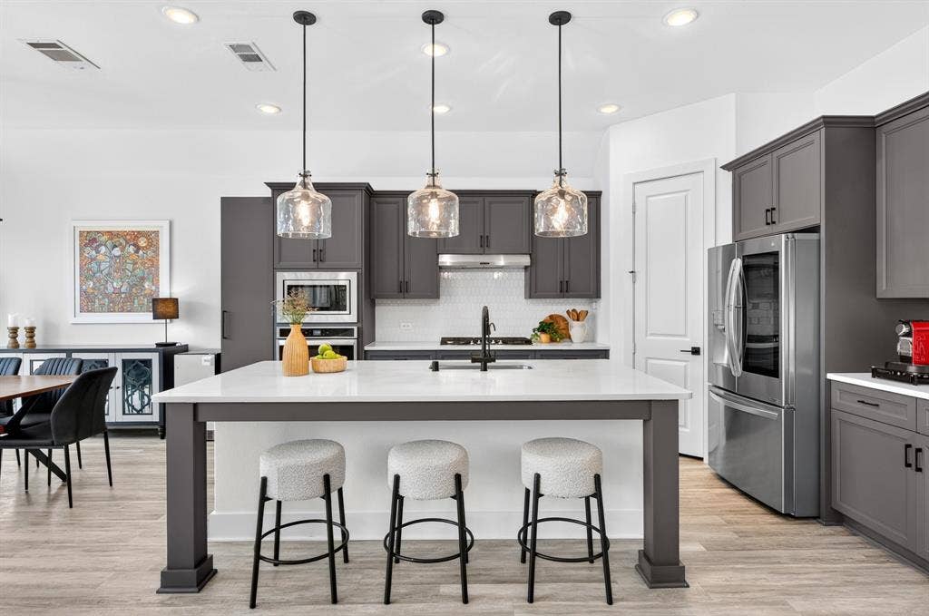 2809 Buckskin Lane, Northlake, TX 76247 Kitchen featuring a center island with countertop seating, dark gray cabinetry, stainless steel appliances, and wood-finish flooring