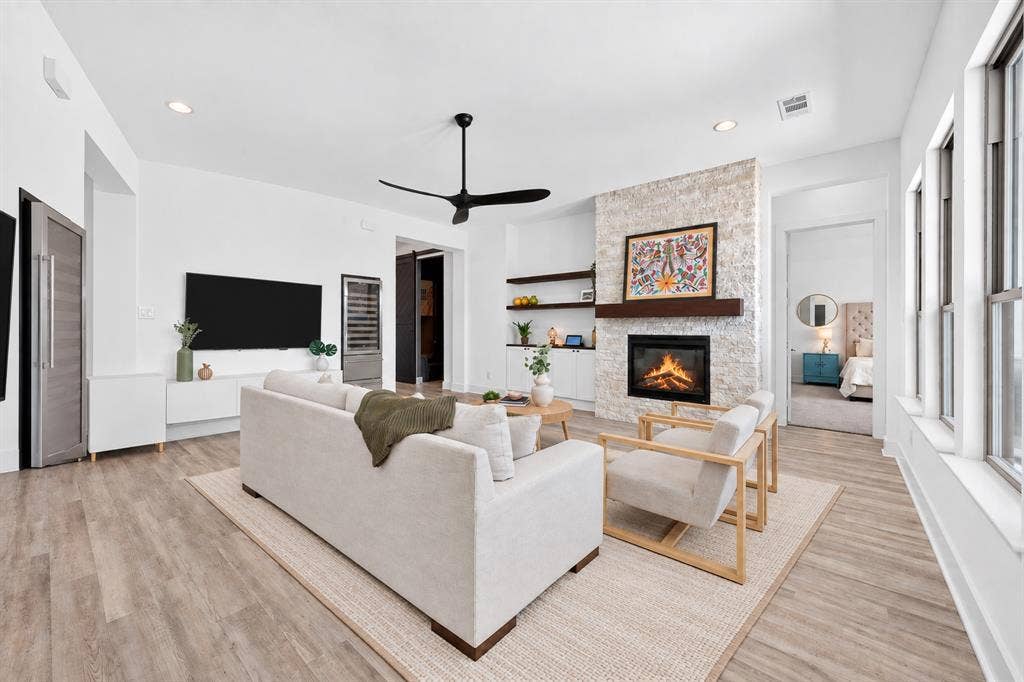 2809 Buckskin Lane, Northlake, TX 76247 White stone-clad fireplace with a wood mantle, wood-finish flooring, recessed lighting, and a contemporary ceiling fan