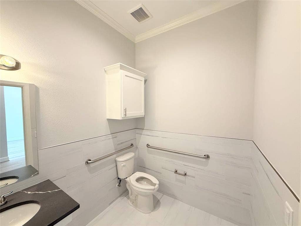 2120 Prairie Drive, #902, Prosper, TX 75078 Bathroom featuring a dark countertop with a contrasting white vessel sink, wall-mounted white cabinetry, and white wall-mounted tile