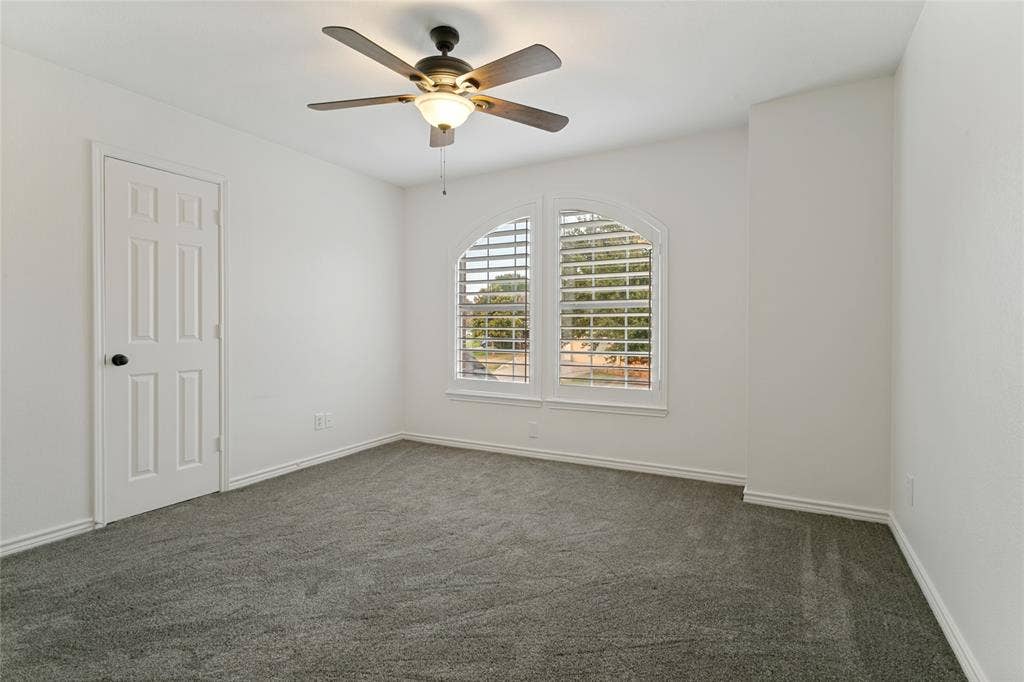 17 Adams Court, Mansfield, TX 76063 Arched window with plantation shutters, ceiling fan with integrated lighting, paneled door, and neutral carpet flooring