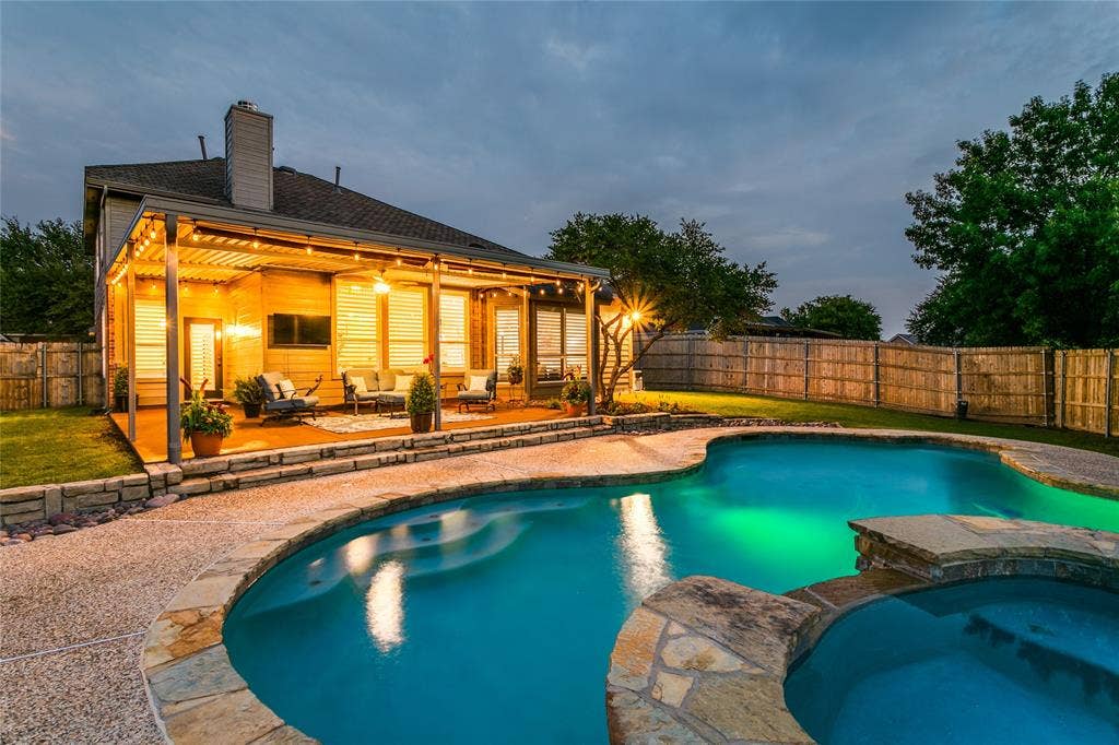 17 Adams Court, Mansfield, TX 76063 Expansive outdoor living area featuring a covered patio with string lighting, a freeform swimming pool, an integrated spa, and stone coping