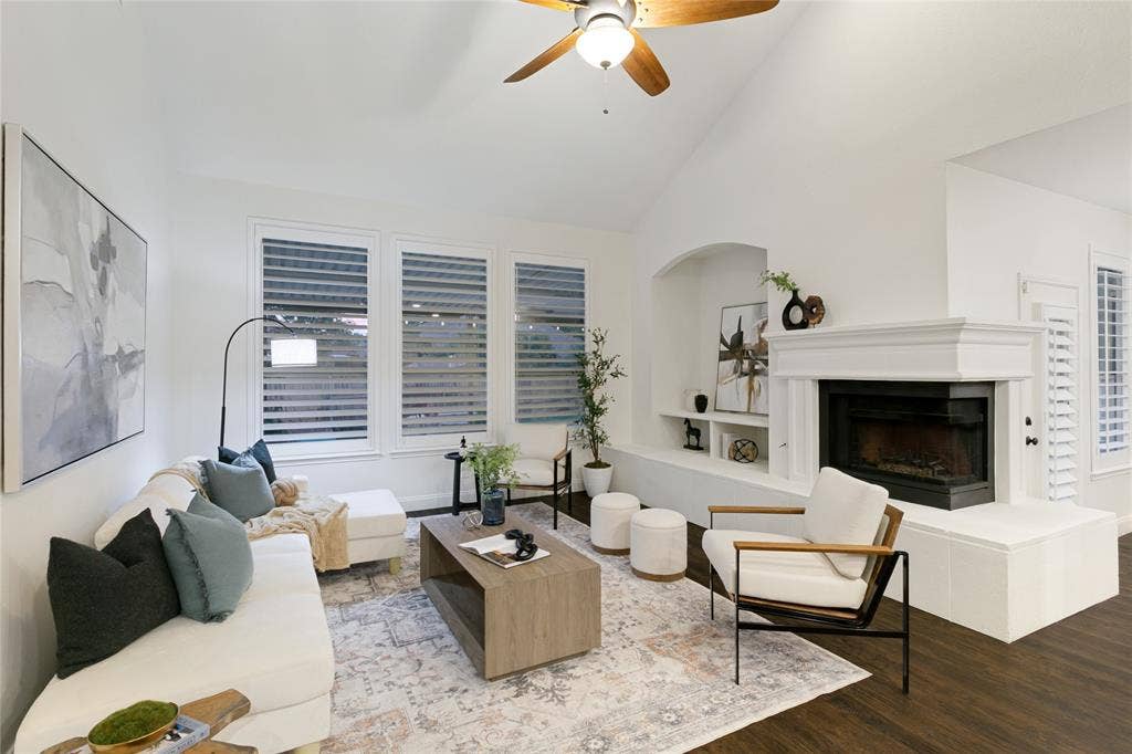 17 Adams Court, Mansfield, TX 76063 Vaulted ceiling with a ceiling fan, fireplace with a decorative mantel, built-in shelving, wood-finish flooring, and window shutters
