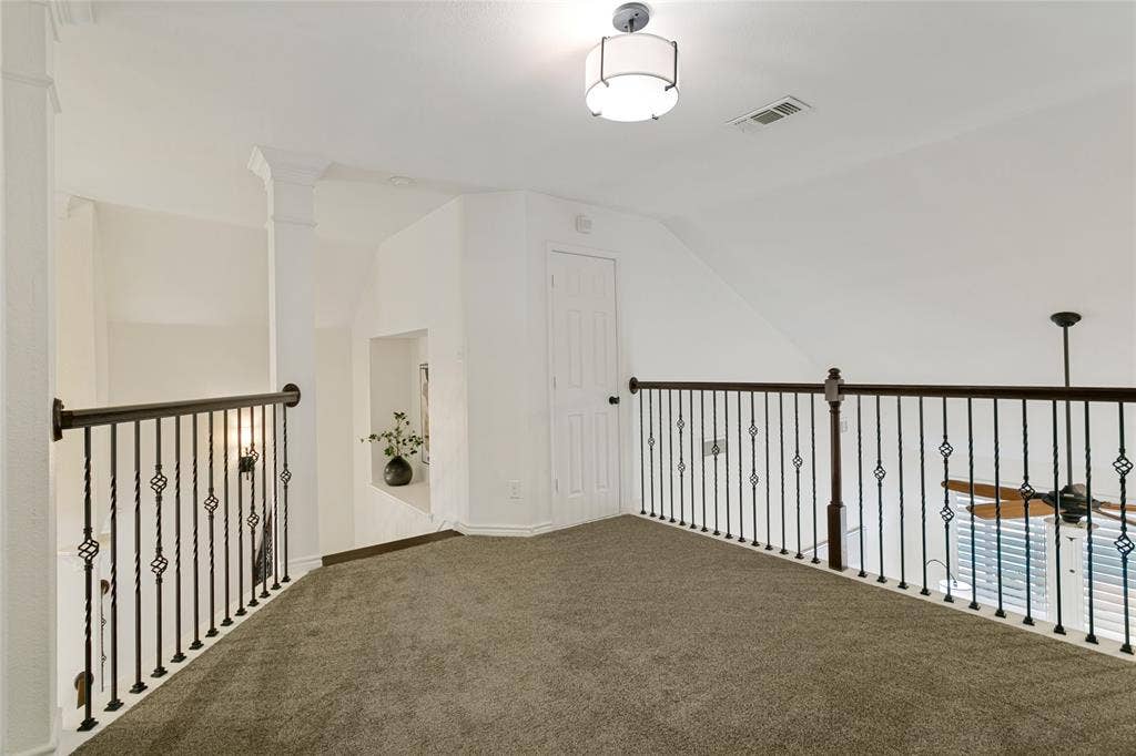 17 Adams Court, Mansfield, TX 76063 Carpeted loft area featuring wrought iron railings, a built-in display nook, a flush mount light fixture, and a ceiling fan