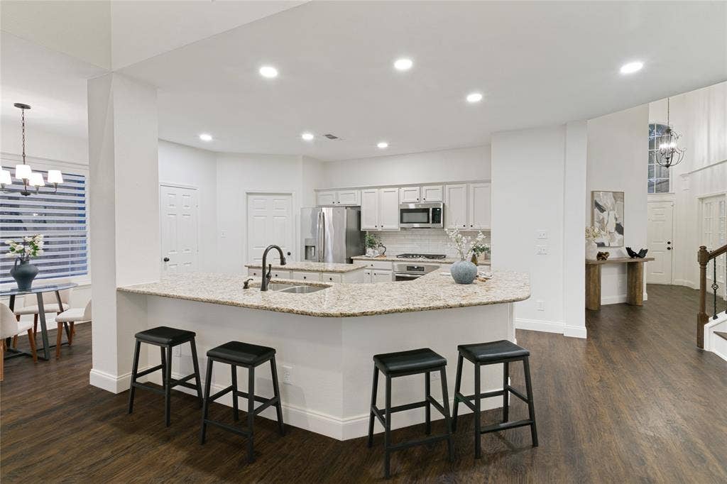 17 Adams Court, Mansfield, TX 76063 Open-concept kitchen featuring an expansive island with a built-in sink, stainless steel appliances, white cabinetry, and recessed lighting