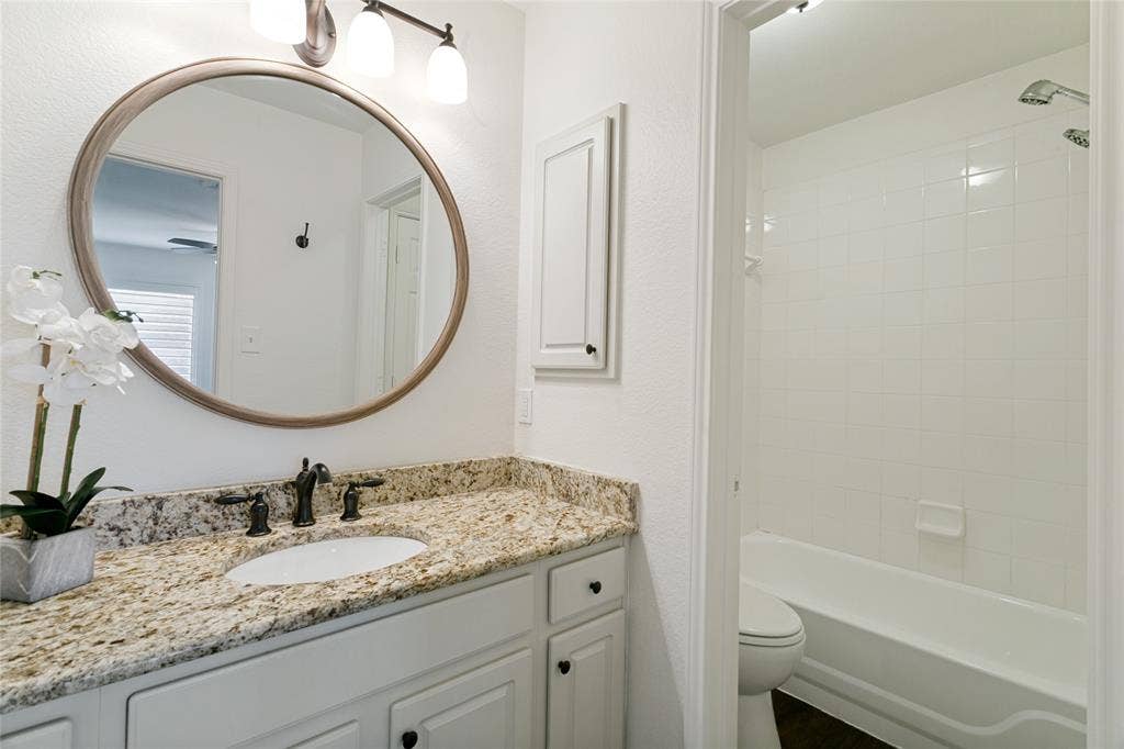 17 Adams Court, Mansfield, TX 76063 Bathroom featuring a vanity with a light-toned countertop, a dark-toned faucet, and a round framed mirror