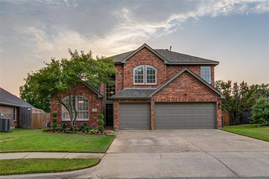 17 Adams Court, Mansfield, TX 76063 Traditional brick exterior with an attached three-car garage, freshly installed landscaping, and an arched window detail.