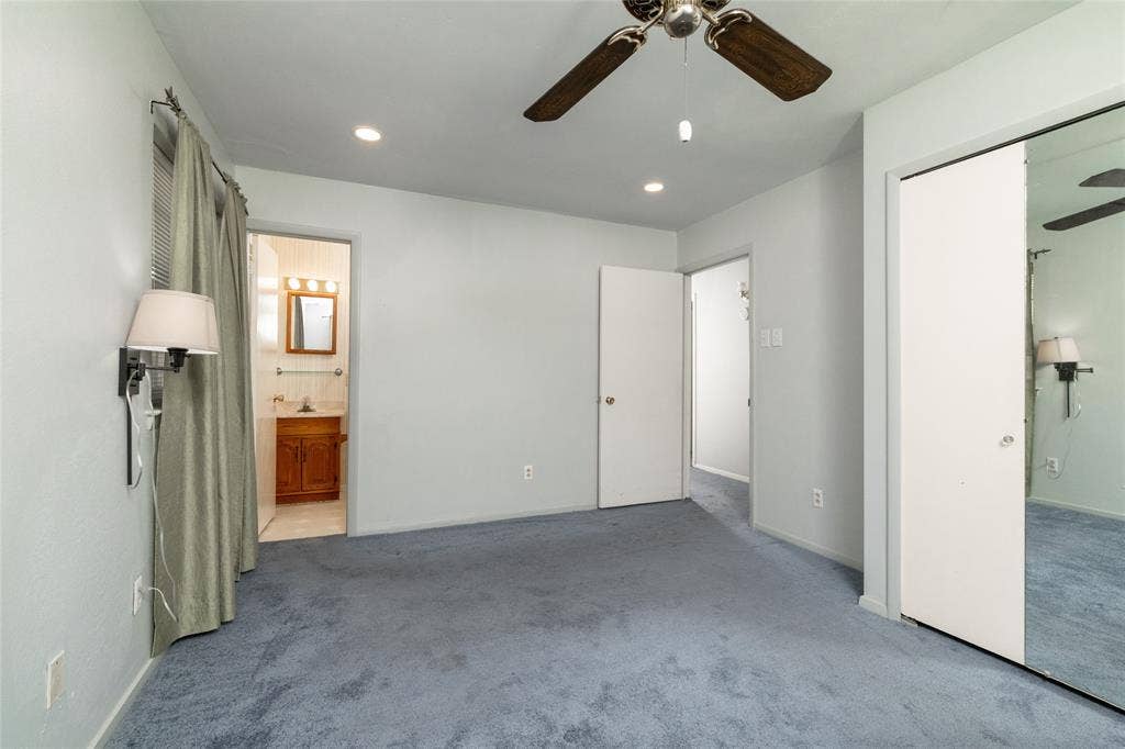 Spacious primary bedroom retreat with plush carpeting, ceiling fan with integrated lighting, and direct access to an ensuite bathroom