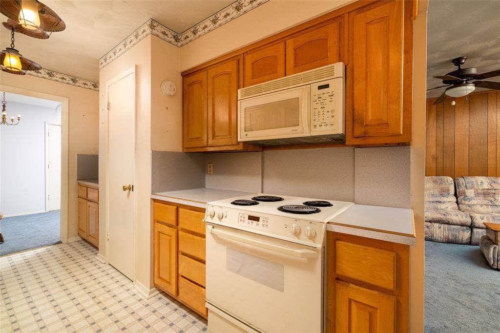 Kitchen featuring wood cabinetry, white countertops, and white appliances including a range and over-the-range microwave