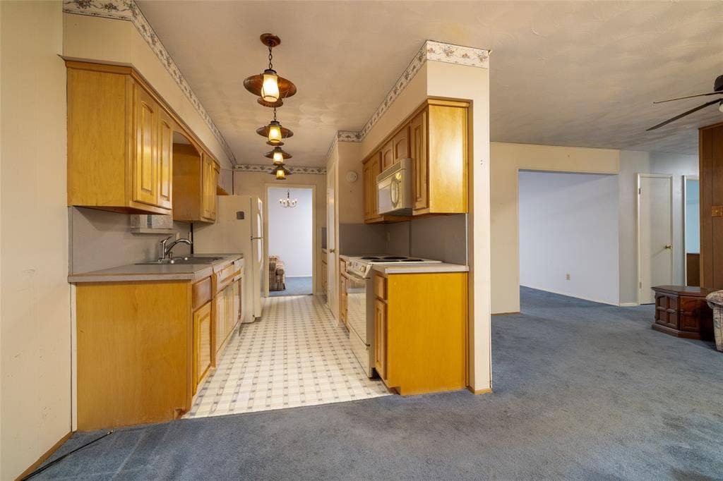 Wood-finish cabinetry with laminate countertops, a stainless steel sink, and a tiled backsplash