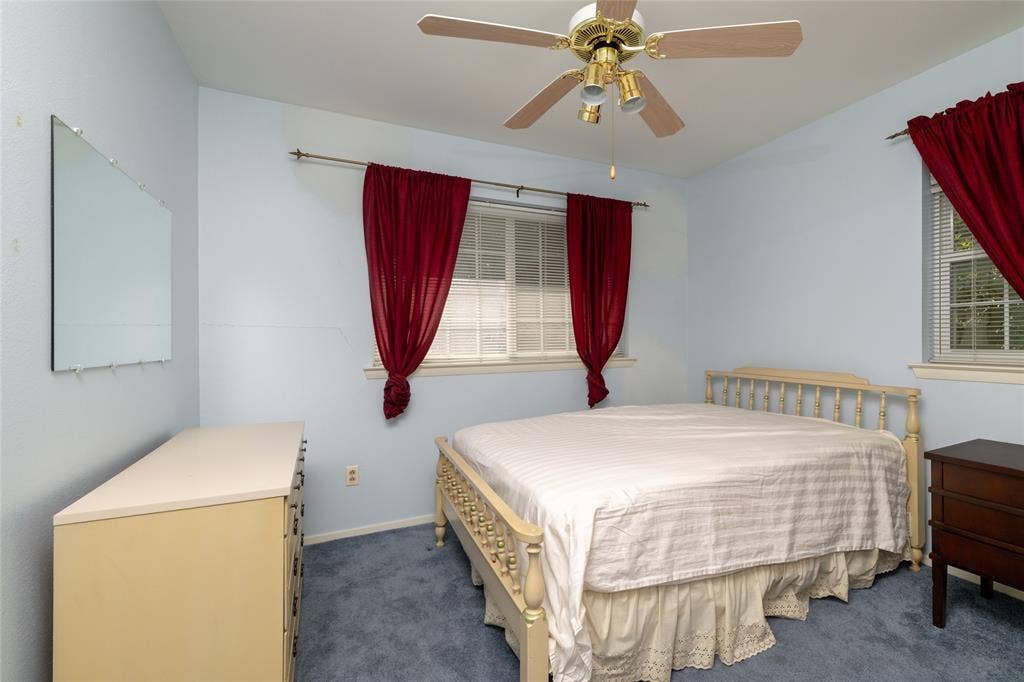 Room featuring light blue walls, blue carpet, and two windows with white blinds