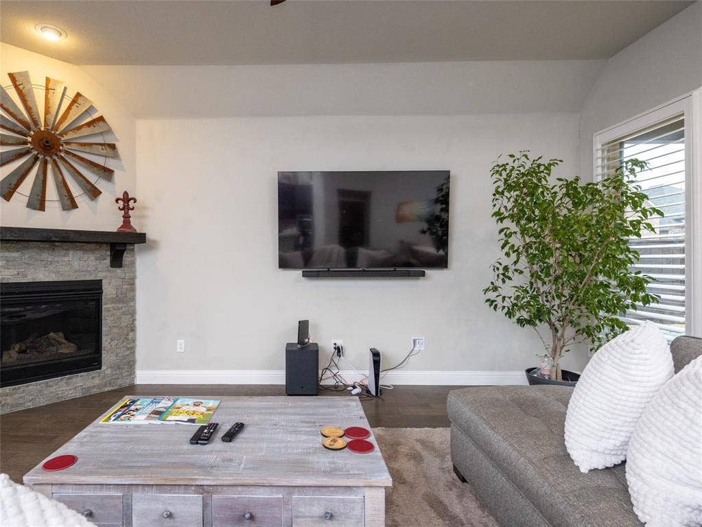 Corner fireplace featuring a stone surround and wood mantel