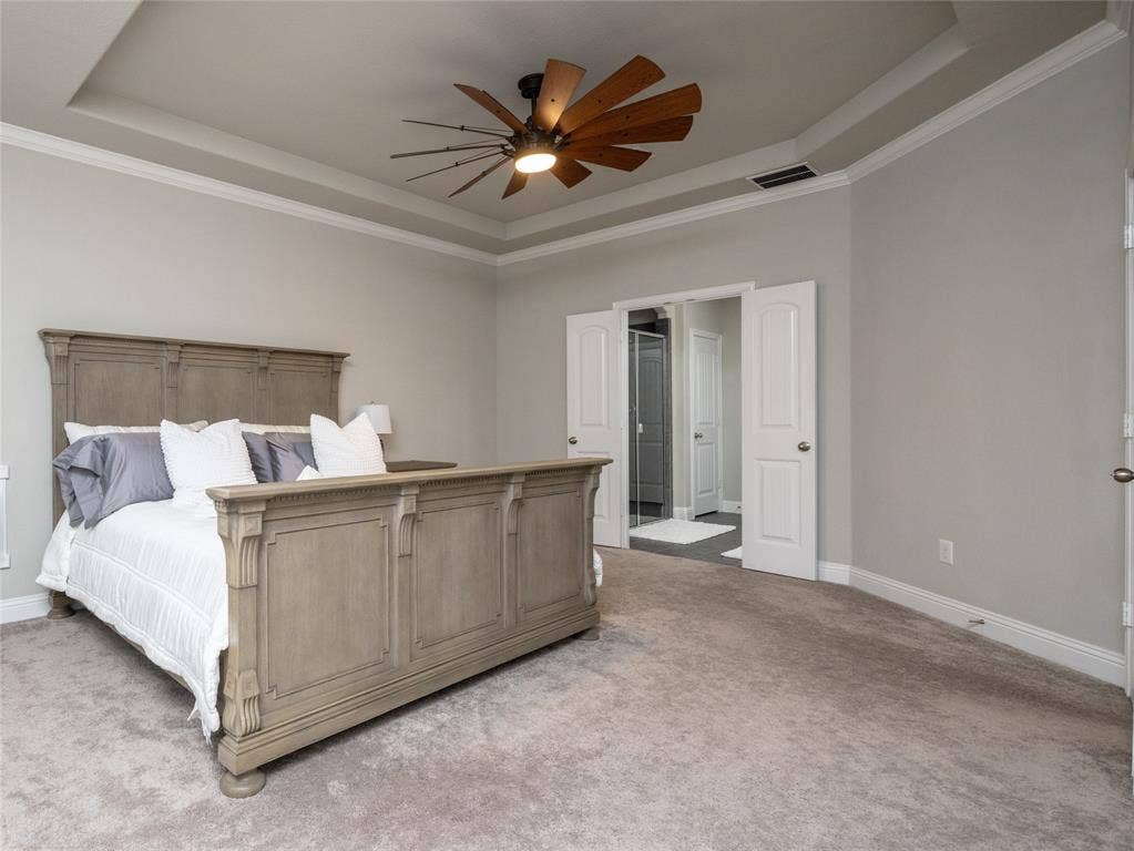 Tray ceiling with crown molding, ceiling fan, and light gray wall paint