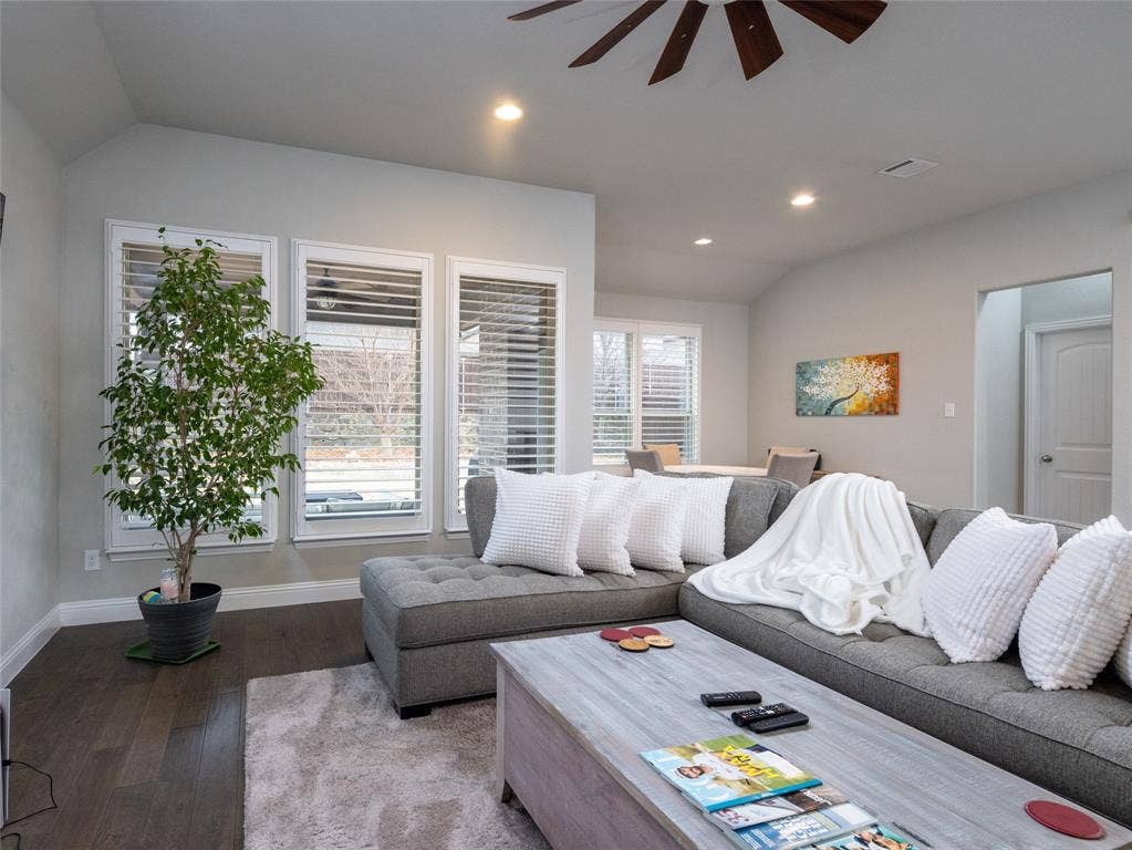 Vaulted ceiling with a ceiling fan, recessed lighting, wood-finish flooring, and multiple windows with blinds