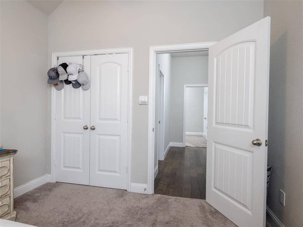 Vaulted ceiling, white paneled doors, light gray wall color, gray carpet, and wood-finish flooring