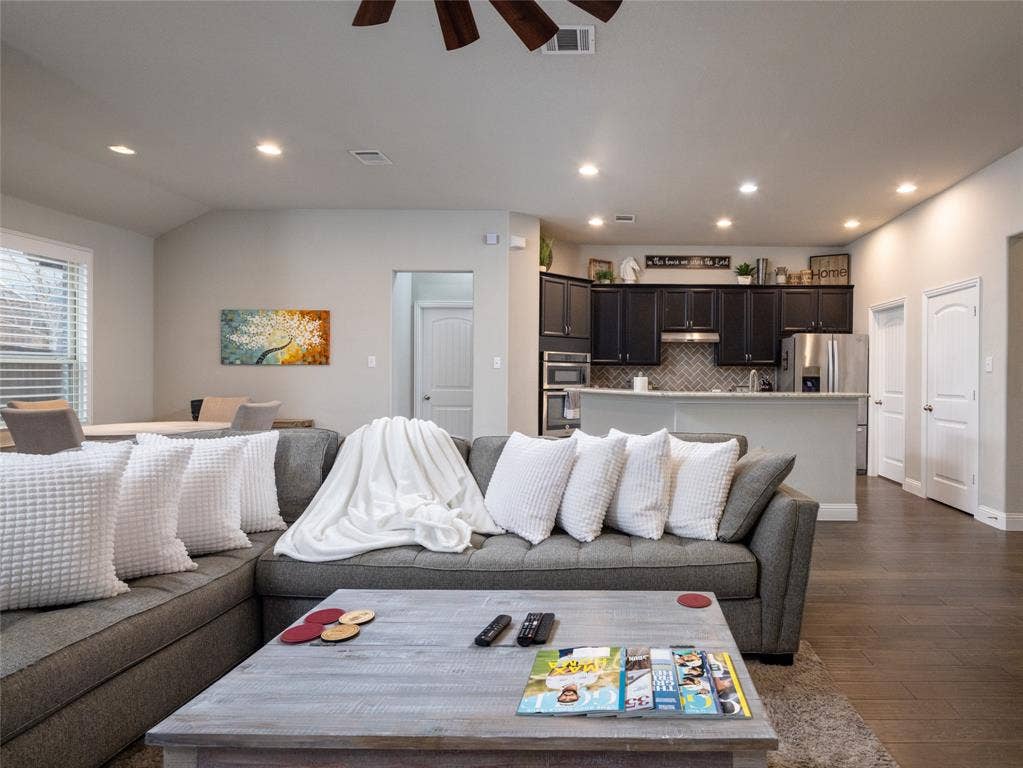 Recessed lighting, wood-finish flooring, dark cabinetry, stainless steel appliances, and a tiled kitchen backsplash