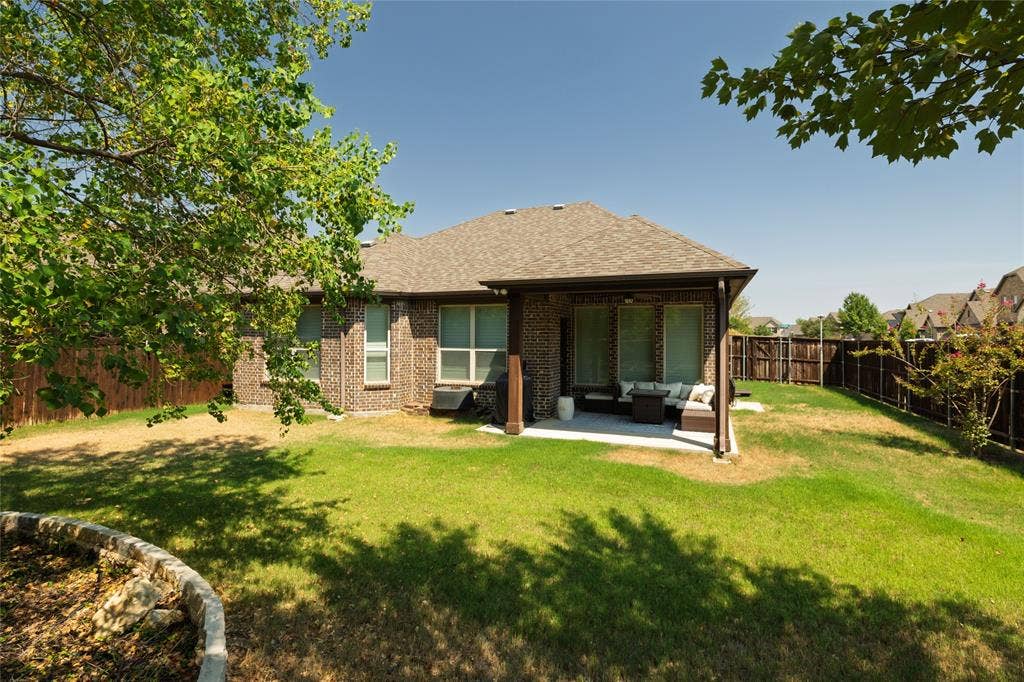 Expansive lawn featuring a covered patio with recessed lighting, full brick exterior, and a privacy fence
