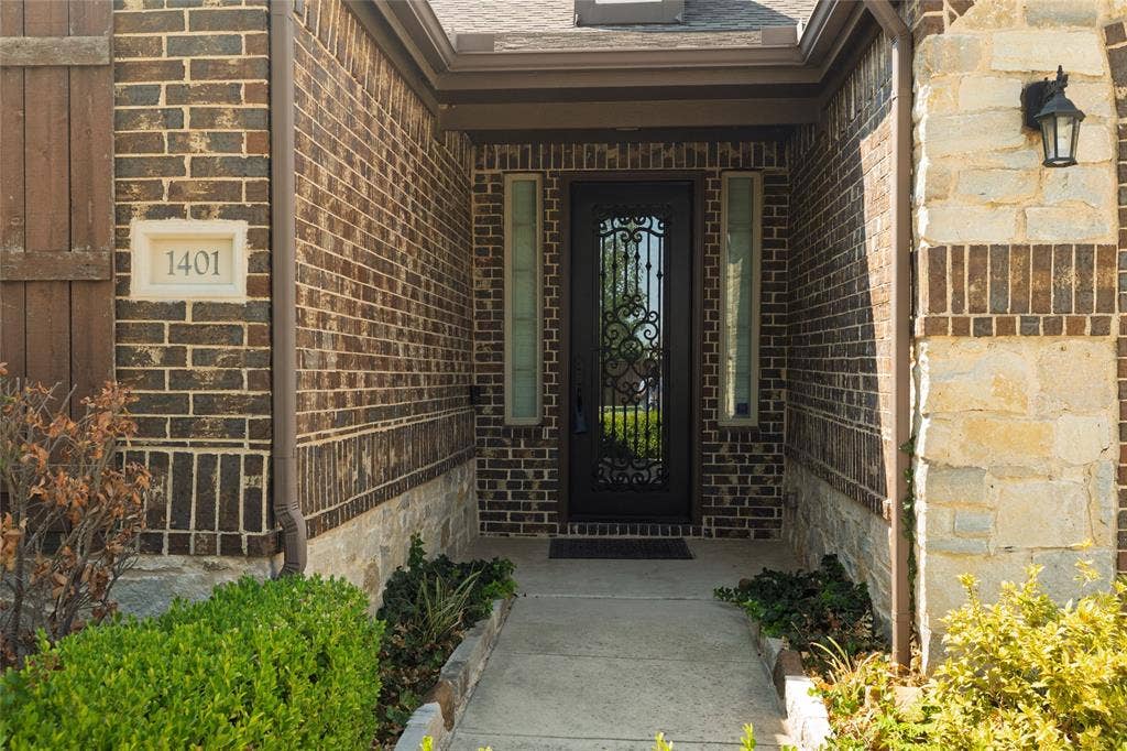 Brick exterior with stone accents and a decorative iron entry door