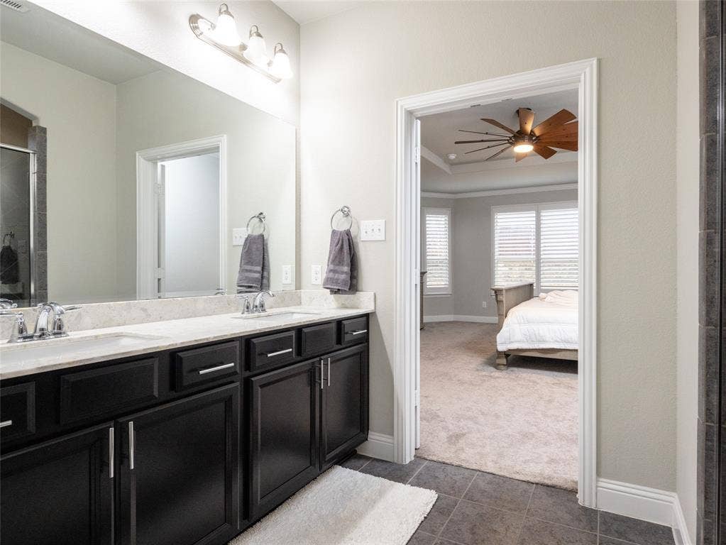 Dual vanity with dark wood-finish cabinetry, light-toned countertop, and chrome fixtures