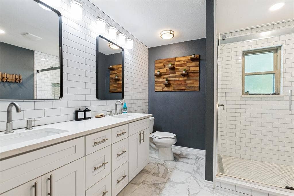 Dual vanity with white shaker-style cabinetry, undermount sinks, and contemporary wall-mounted lighting