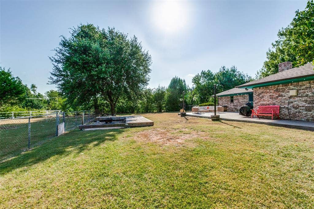 Expansive green space with mature trees, a chain-link fence, and a brick-clad exterior